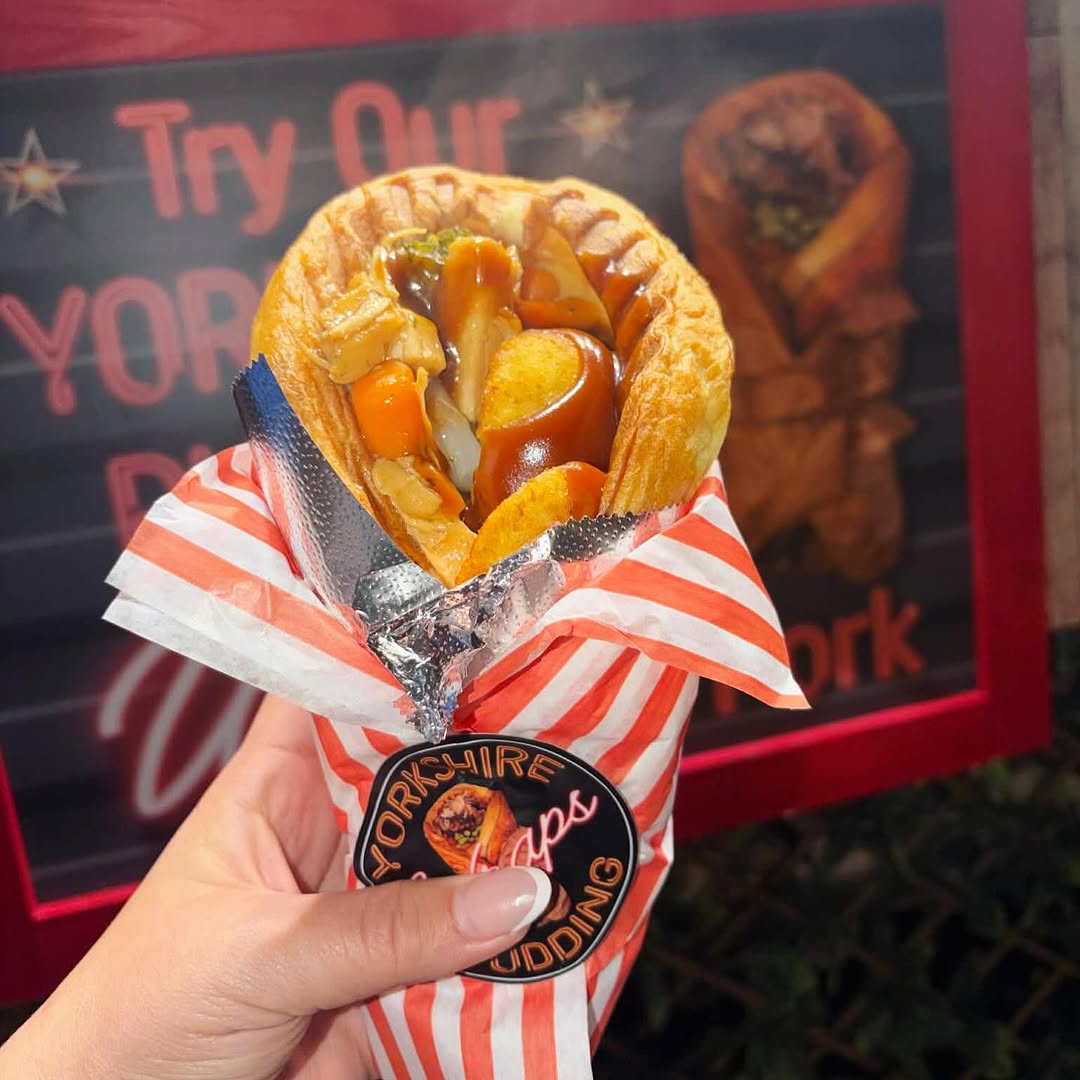 A Yorkshire pudding wrap held up in front of the food stall