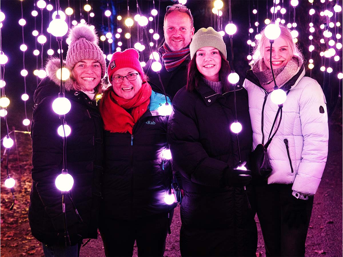 A group of friends in hats and scarves among glowing lights
