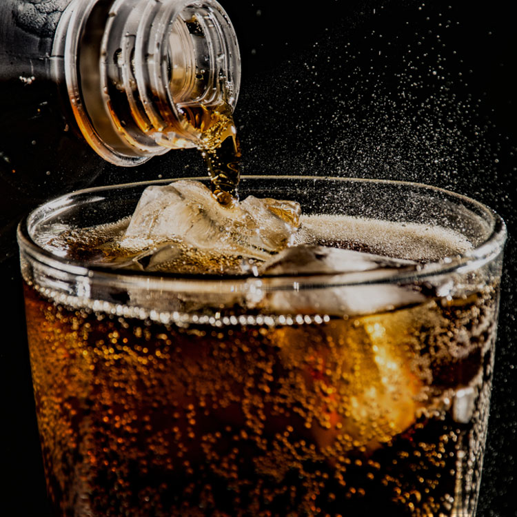 A cold drink being poured over ice