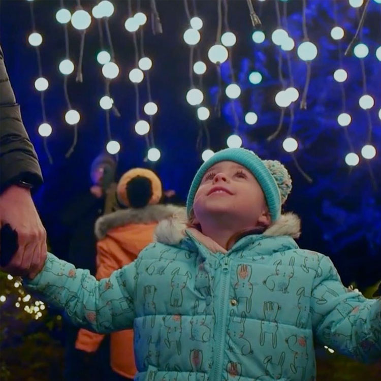 A child looking up at hanging globes of light