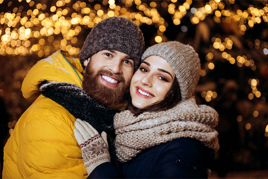 A couple wrapped up warm under festoon lights