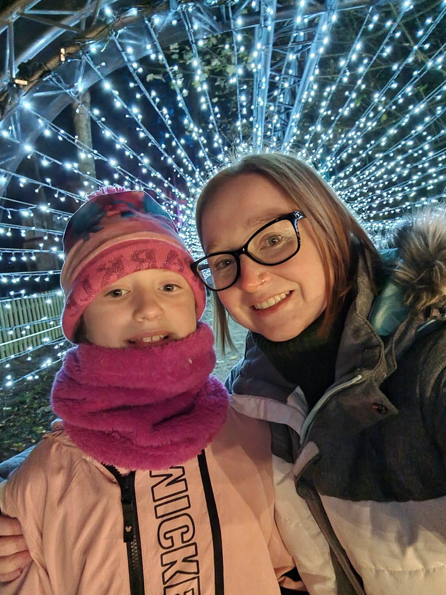 A mum and her daughter smiling inside a tunnel of lights
